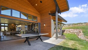 A modern house with a spacious patio, a ping pong table, and a stone wall. - Red Ledges cottage, golf, min 90 day stay (Heber City)