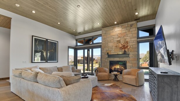 A modern living room with a stone fireplace, large windows, and a leather rug. - Red Ledges cottage, golf, min 90 day stay (Heber City)
