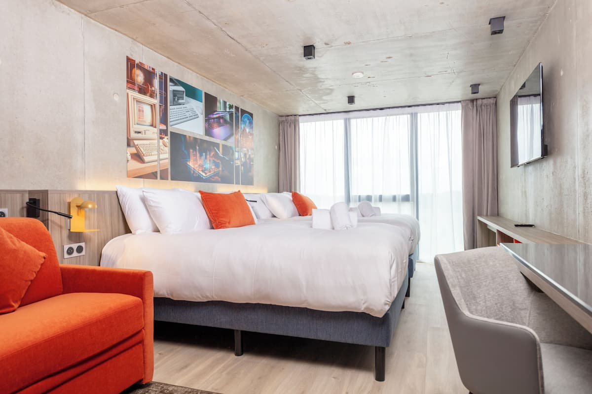 A modern hotel room with a large bed, a desk, and a TV.