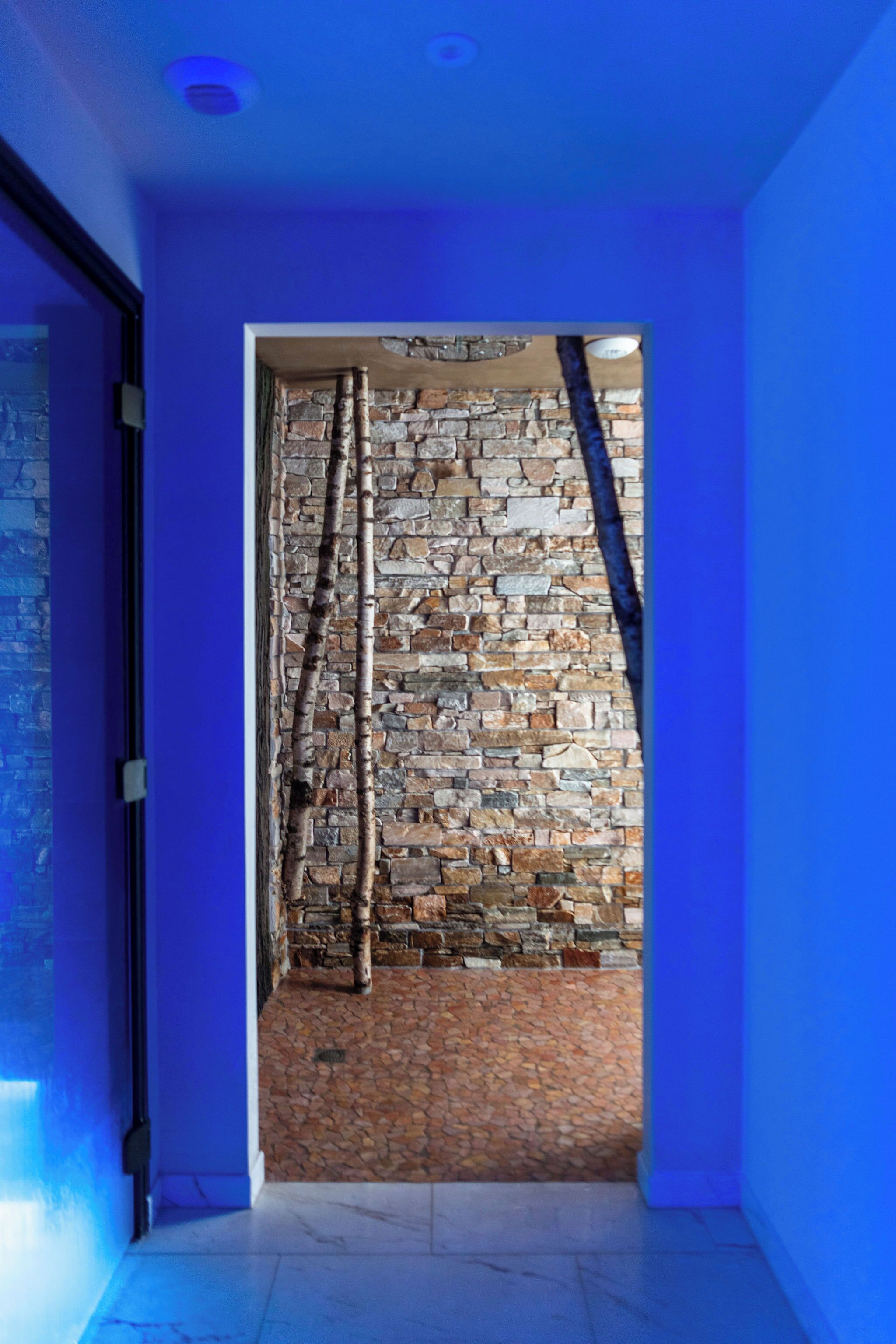 Un pasillo con pared de piedra y marco de puerta iluminado en azul.