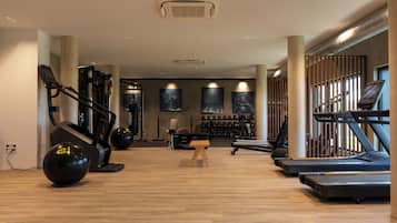 Une salle de sport équipée de tapis de course, de vélos elliptiques et de poids libres.