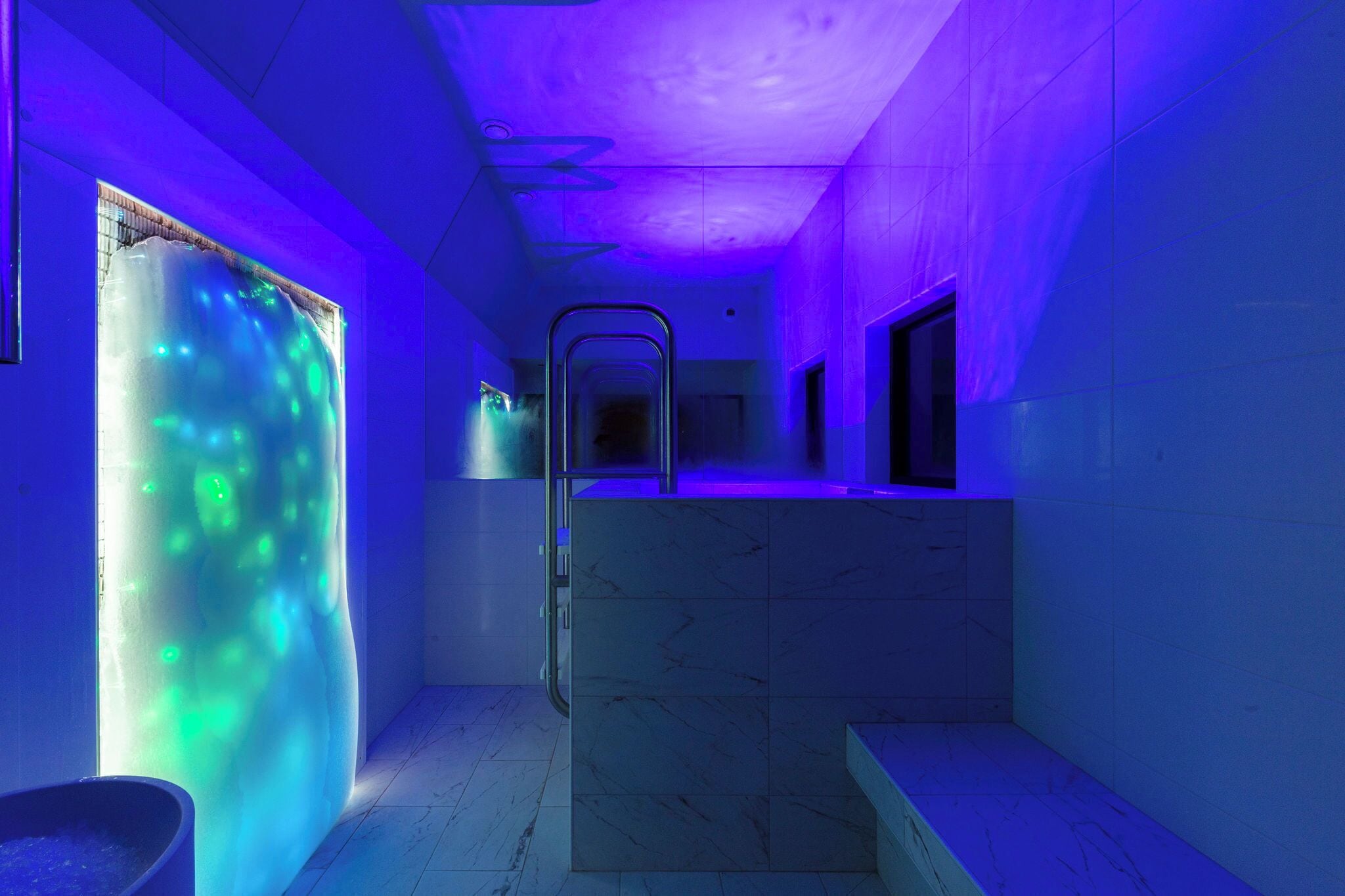 A modern bathroom with a glass enclosure, a metal ladder, and a marble sink.