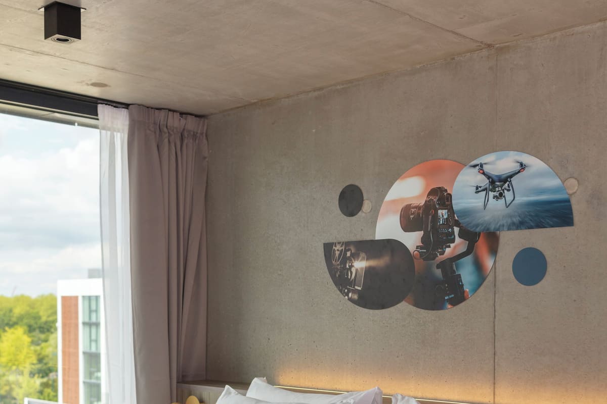 A hotel room with a large bed, a view of the outdoors, and a wall with a circular design.