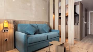 Un salon moderne avec un canapé bleu, une petite table d’appoint et un meuble en bois doté d’une étagère intégrée.