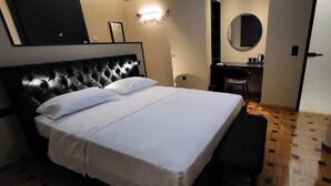 A hotel room with a large bed, a bedside table, a mirror, and a small desk with a chair. - LView Zeus Temple (Athens)