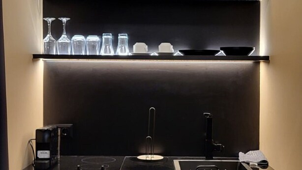 A compact kitchen with a built-in stove, a sink, and a shelf with glassware. - LView Zeus Temple (Athens)