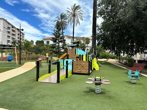 Un parque infantil con tobogán, columpios y estructuras para escalar.