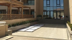A multi-story hotel with a central glass facade, a covered outdoor seating area, and a paved courtyard. - Sea View Duplex Villa Hurghada  (Red Sea Governorate)