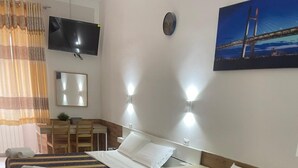 A hotel room with a bed, bedside tables, a TV, a clock, and a painting on the wall. - Hotel Roma Palace (Rome)