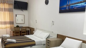 A hotel room with two beds, a desk, a chair, a TV, and a painting of a bridge. - Hotel Roma Palace (Rome)