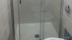 A glass-enclosed shower stall with tiled walls and a visible drain. - Hotel Roma Palace (Rome)