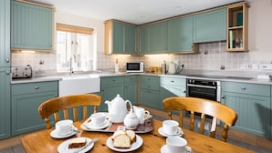 Una cocina moderna con armarios color turquesa, una mesa de comedor de madera y una zona para desayunar.