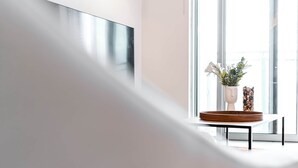A modern interior with a minimalist design, featuring a white table with a wooden tray and two vases with flowers and decorative items.