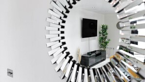 Um interior moderno com escada circular, televisão de tela plana na parede e planta em vaso.