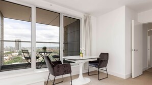 A modern room with a large window, a round table, two chairs, and a view of the cityscape. - The Ferre - Canary Wharf (London)