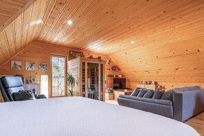 Cozy cabin retreat with a large bed, sofa, and armchair, perfect for relaxing.