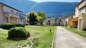 Un carrer residencial amb cases, un camí de grava i una muntanya al fons.