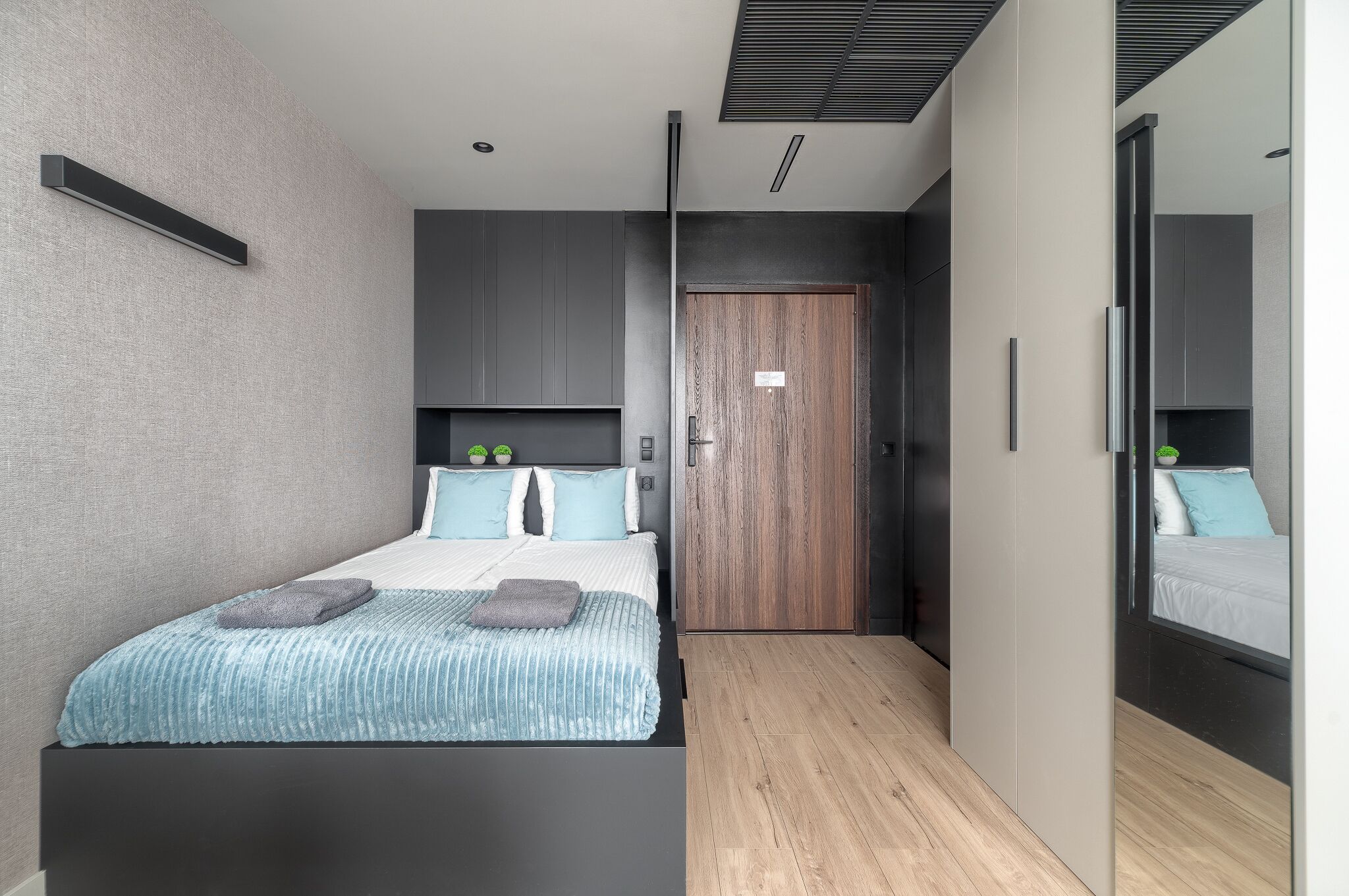 A modern bedroom with a bed, bedside tables, and a wardrobe.
