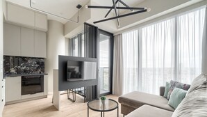 A modern living space with a kitchen, a flat-screen TV, a sofa, and a dining area. - MARGI Smart Apartment  (Szczecin)