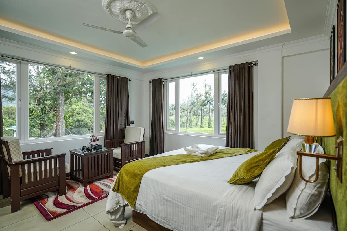 A hotel room with a large bed, a desk, a chair, and a view of the outdoors.