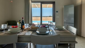 Een eethoek met een tafel voor vier personen, met uitzicht op een zwembad en het landschap.
