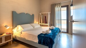 Een slaapkamer met een bed, een nachtkastje met lamp, een kledingkast en uitzicht door een deur.