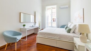 Quarto com cama, escrivaninha, cadeira e mesa de cabeceira com abajur.