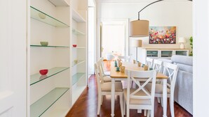 Uma sala de estar moderna com área de refeições, prateleiras de vidro e um quadro na parede.