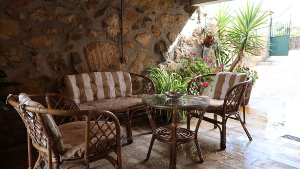 Un patio con paredes de piedra, muebles de mimbre y plantas en macetas.