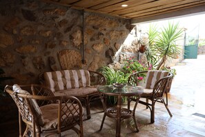 Un patio con paredes de piedra, muebles de mimbre y plantas en macetas.