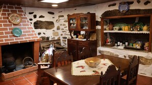 Una cocina rústica con chimenea de ladrillo, armarios de madera y una mesa de comedor con un mantel individual y un bol.
