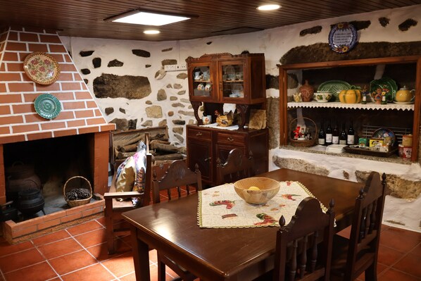 Una cocina rústica con chimenea de ladrillo, armarios de madera y una mesa de comedor con un mantel individual y un bol.