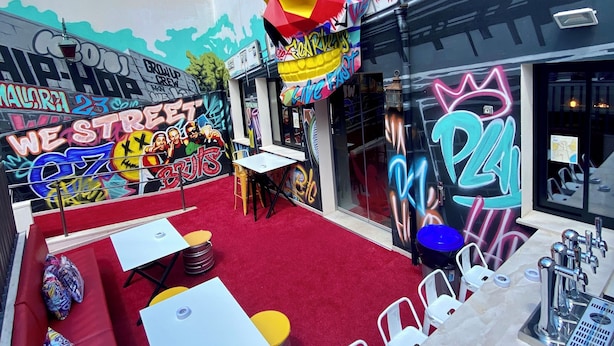 An outdoor seating area with red carpet, tables, and chairs. - We Street Hostel - Albergue Juvenil (Palma de Mallorca)
