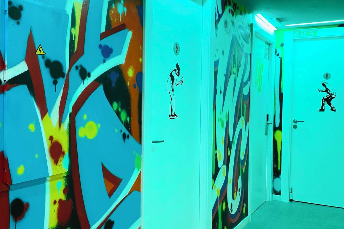 A hallway with doors featuring graffiti art and emergency exit signs.
