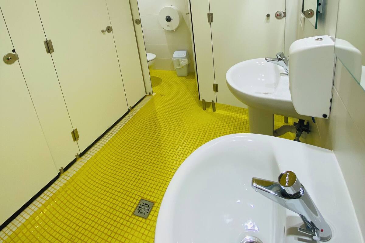 A bathroom with yellow-tiled floors, white lockers, a sink, and a toilet.