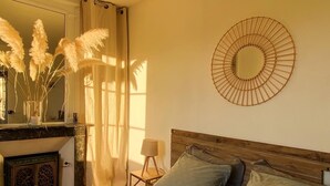 A bedroom with a bed, a mirror, a lamp, and a decorative wall piece. - Chambre D'hôtes de Charme (Bernay)