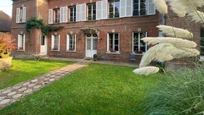 A two-story brick building with a well-maintained lawn and a stone pathway leading to the entrance. - Chambre D'hôtes de Charme (Bernay)