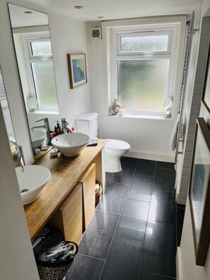 Bathroom features a large mirror, sink, toilet, and window with natural light.