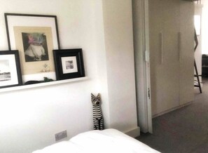 Cozy retreat with a neatly made bed, framed photographs, and a decorative zebra figurine.