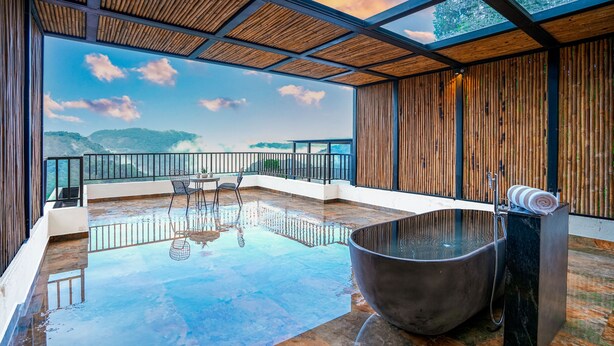 Un vaste espace intérieur doté d’un grand sol réfléchissant, d’un jacuzzi et offrant une vue sur les montagnes.