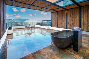 Un vaste espace intérieur doté d’un grand sol réfléchissant, d’un jacuzzi et offrant une vue sur les montagnes.