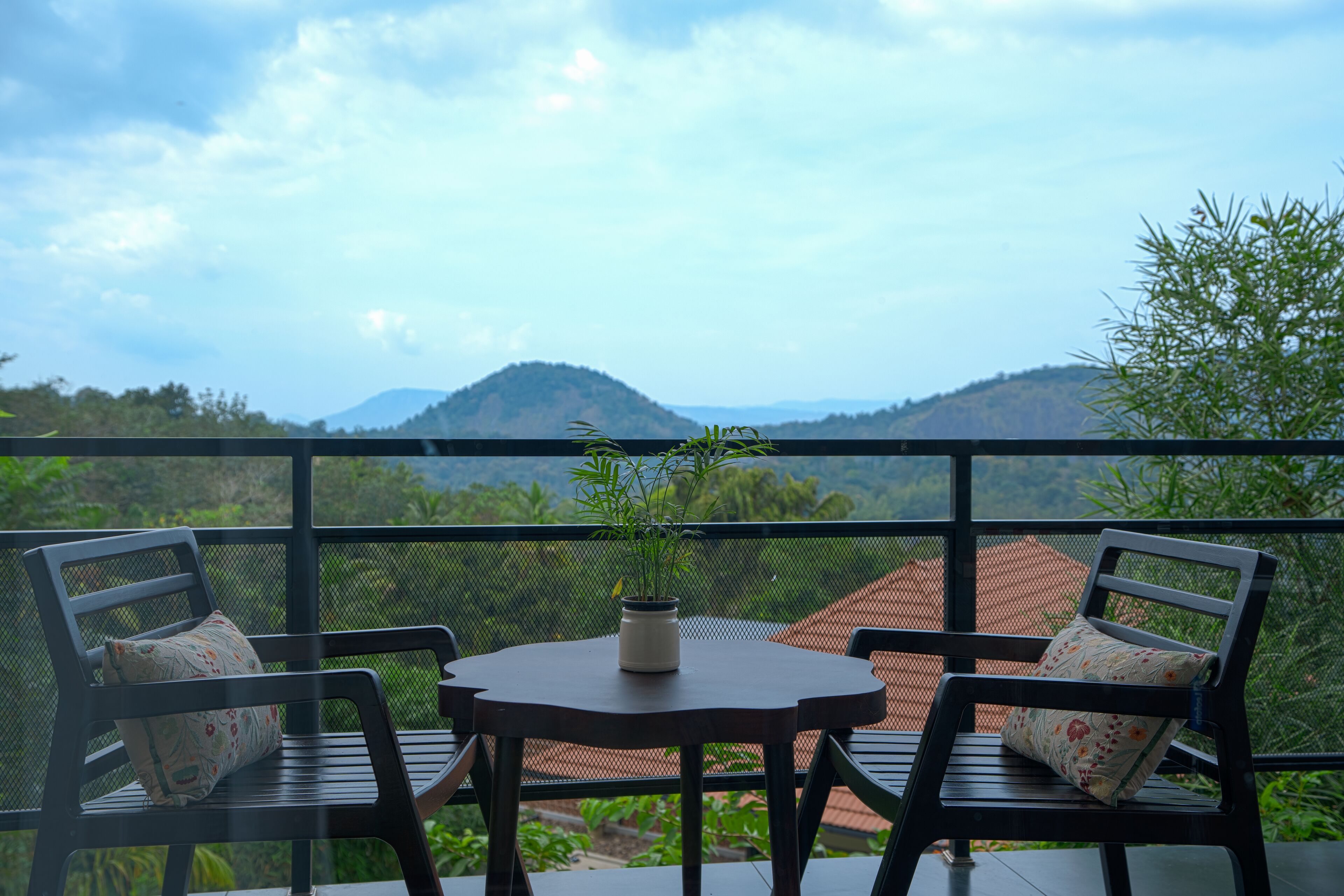 A balcony with two chairs and a table, overlooking a mountainous landscape.