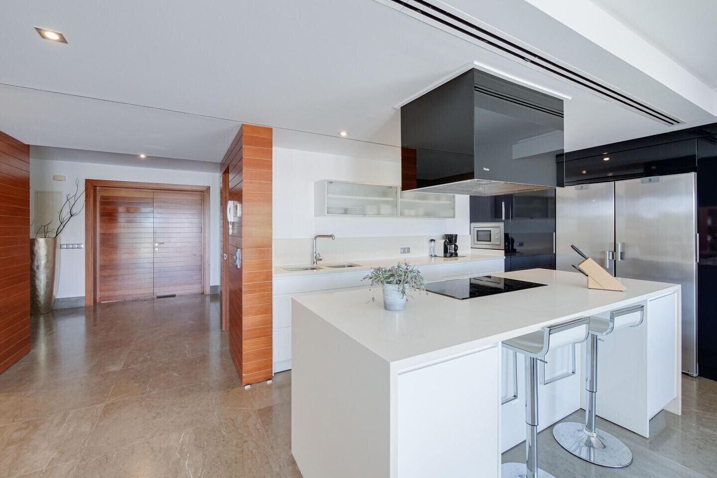 Une cuisine moderne dotée d’un grand îlot central, d’appareils électroménagers en acier inoxydable et d’un design minimaliste.