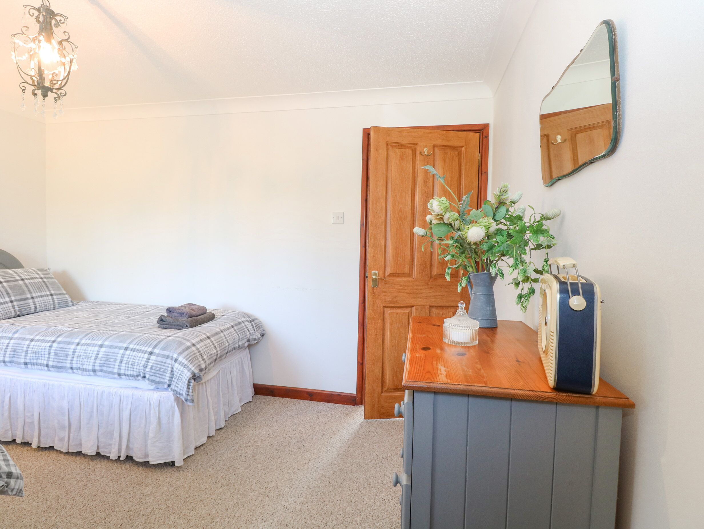 Un dormitorio con cama, cómoda, espejo y puerta.