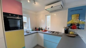 A modern kitchen with a built-in oven, a gas stove, and a window. - Prachtig Designhuis, Rustige Ligging, Zwembad, Speeltuin, Fietsen in de Duinen (De Cocksdorp)