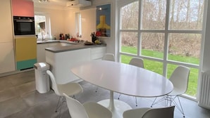 A modern kitchen with a large island, white chairs, and a dining table. - Prachtig Designhuis, Rustige Ligging, Zwembad, Speeltuin, Fietsen in de Duinen (De Cocksdorp)