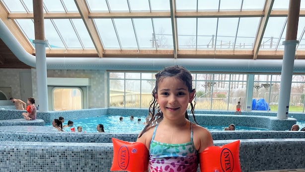 A pool area with tiled flooring, a glass ceiling, and people swimming. - Prachtig Designhuis, Rustige Ligging, Zwembad, Speeltuin, Fietsen in de Duinen (De Cocksdorp)