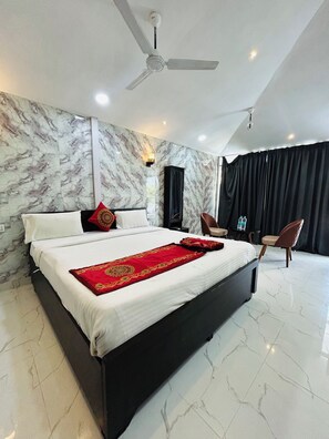 A modern hotel room with a large bed, a ceiling fan, marble walls, and a black curtain.