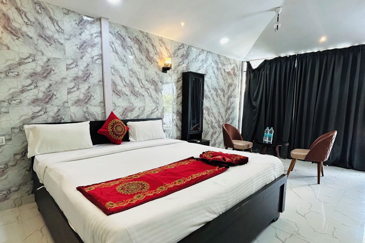 A modern hotel room with a large bed, a ceiling fan, marble walls, and a black curtain.
