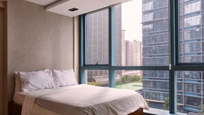 Una camera da letto con una grande finestra, un letto e vista su edifici moderni.